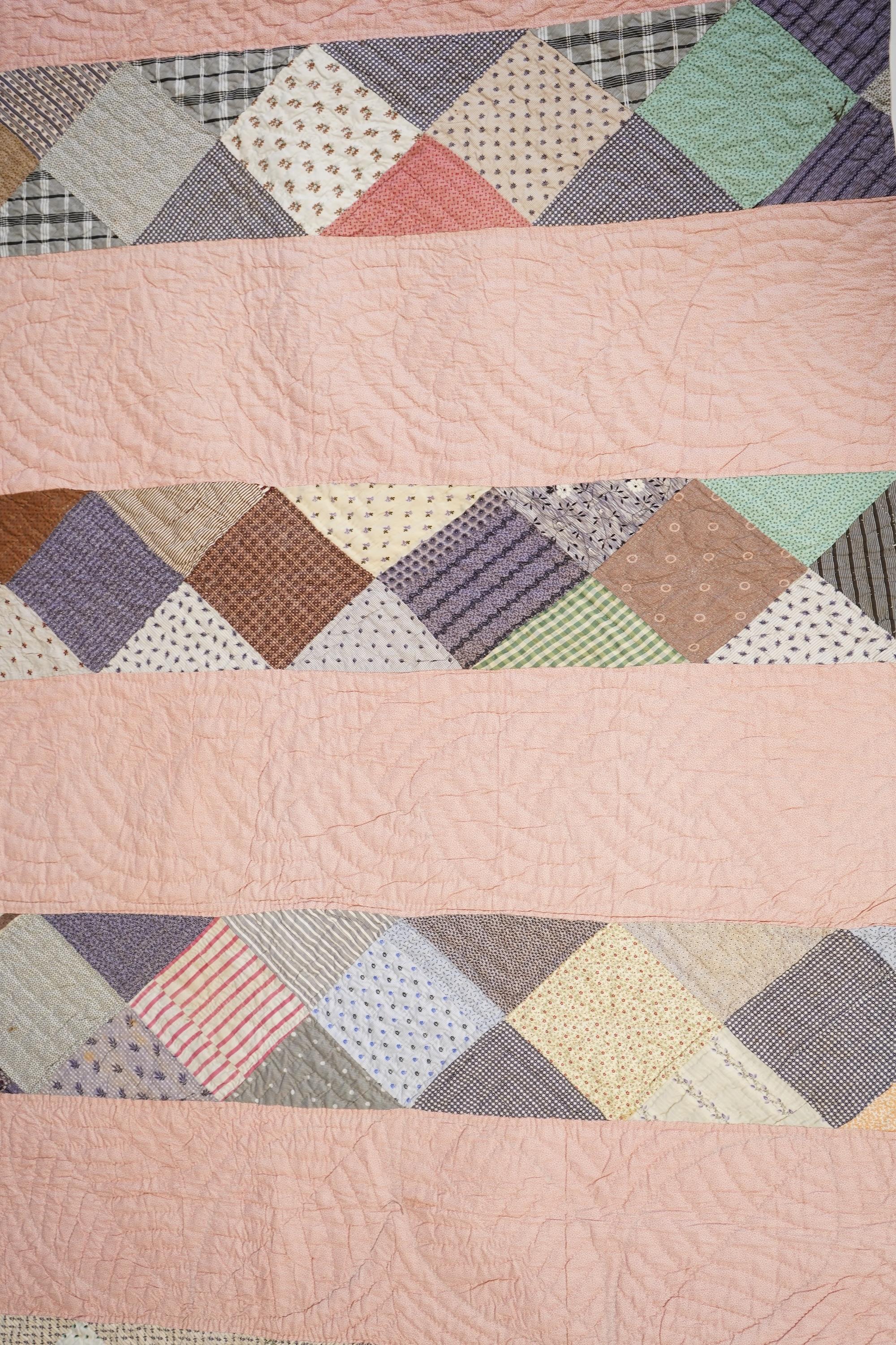 A late 19th century English, possibly ‘North Country’ cotton, hand quilted bed cover. Worked in stripes, with alternate patch worked stripes of differing colour fabrics. Made from fashionable cotton fabrics of the era. R